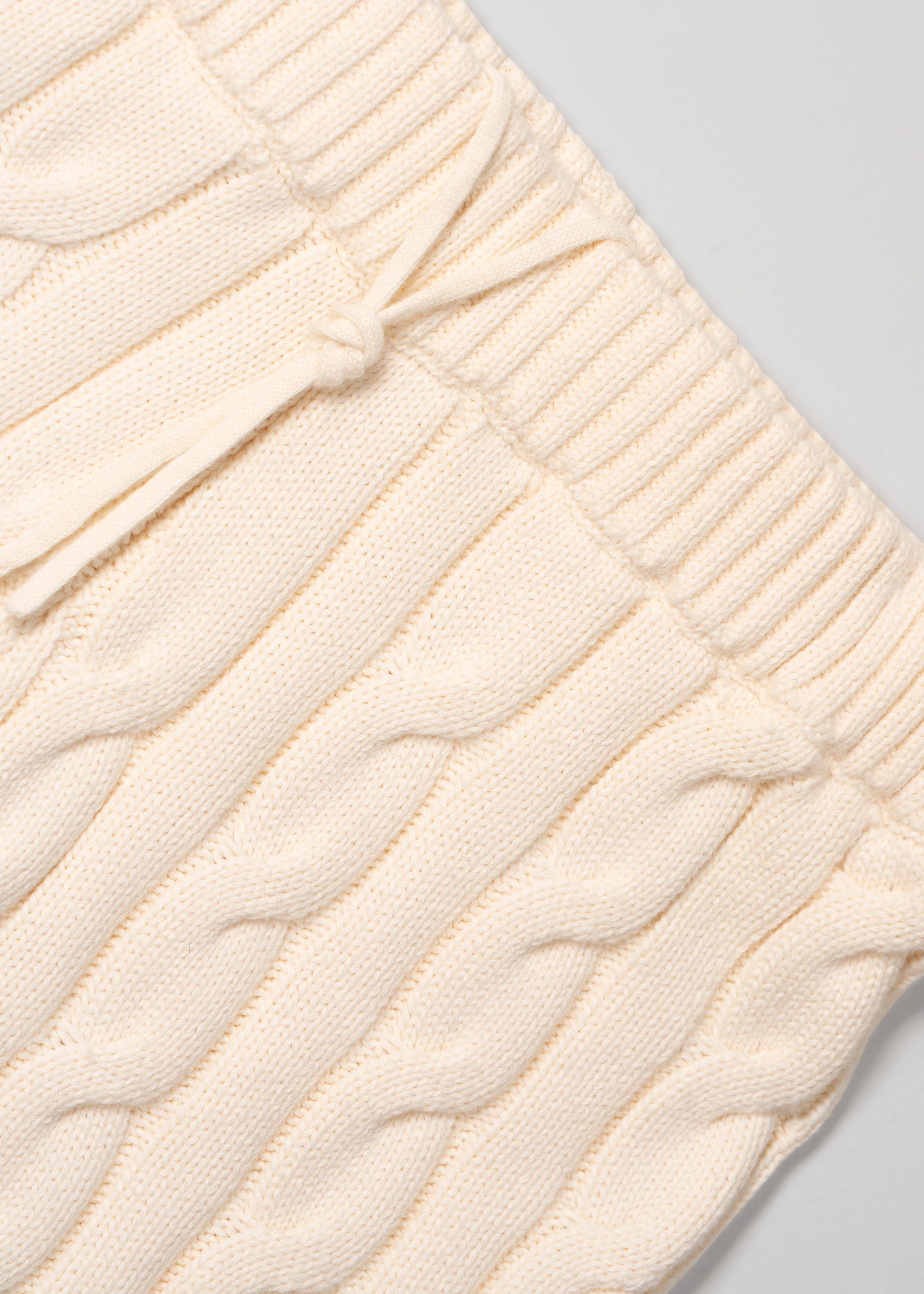 La Corsia Cable Knit Mini Short in cream, made from heavyweight cotton with a fitted silhouette, ribbed waistband, and chunky cable texture throughout.