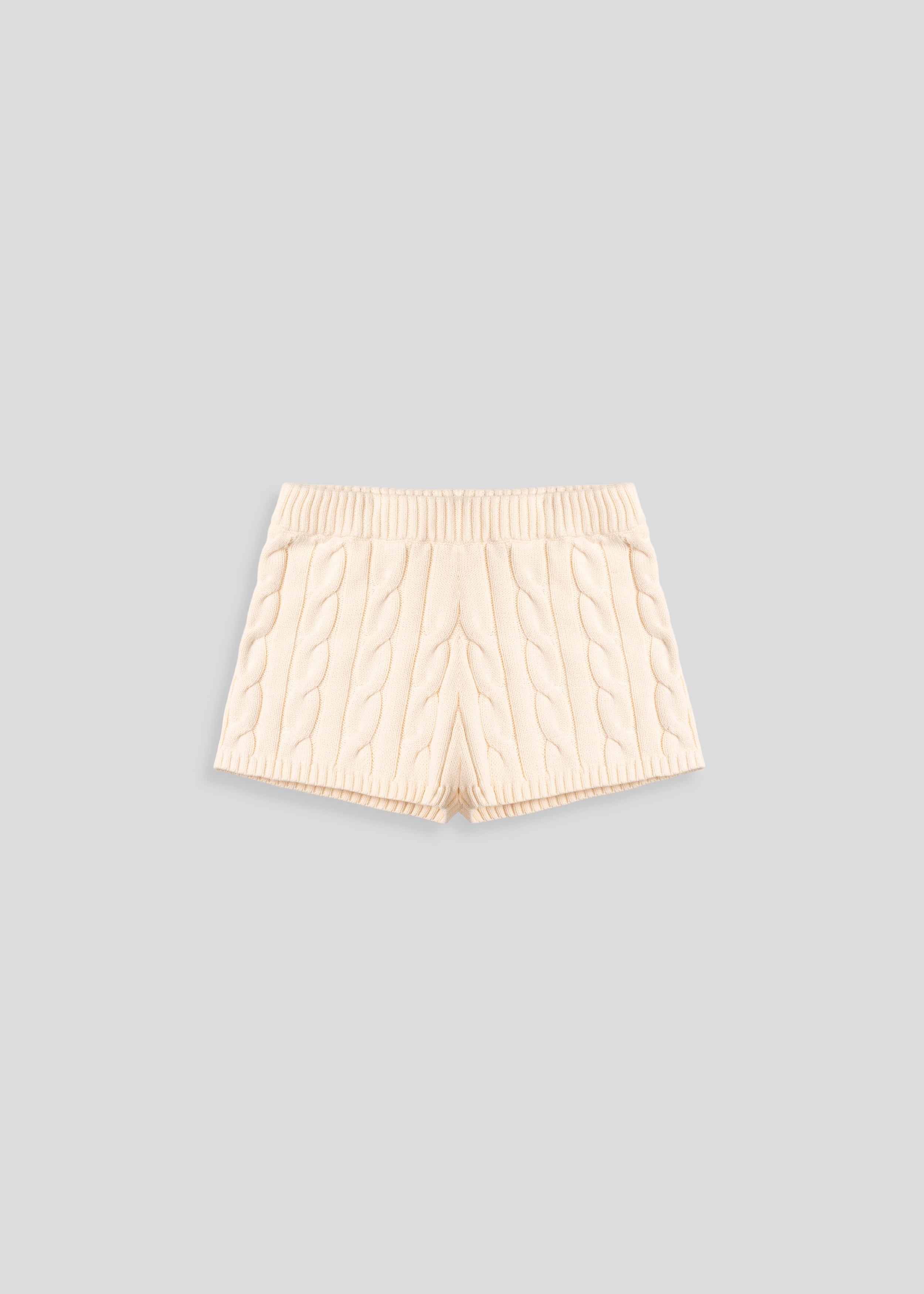 La Corsia Cable Knit Mini Short in cream, made from heavyweight cotton with a fitted silhouette, ribbed waistband, and chunky cable texture throughout.