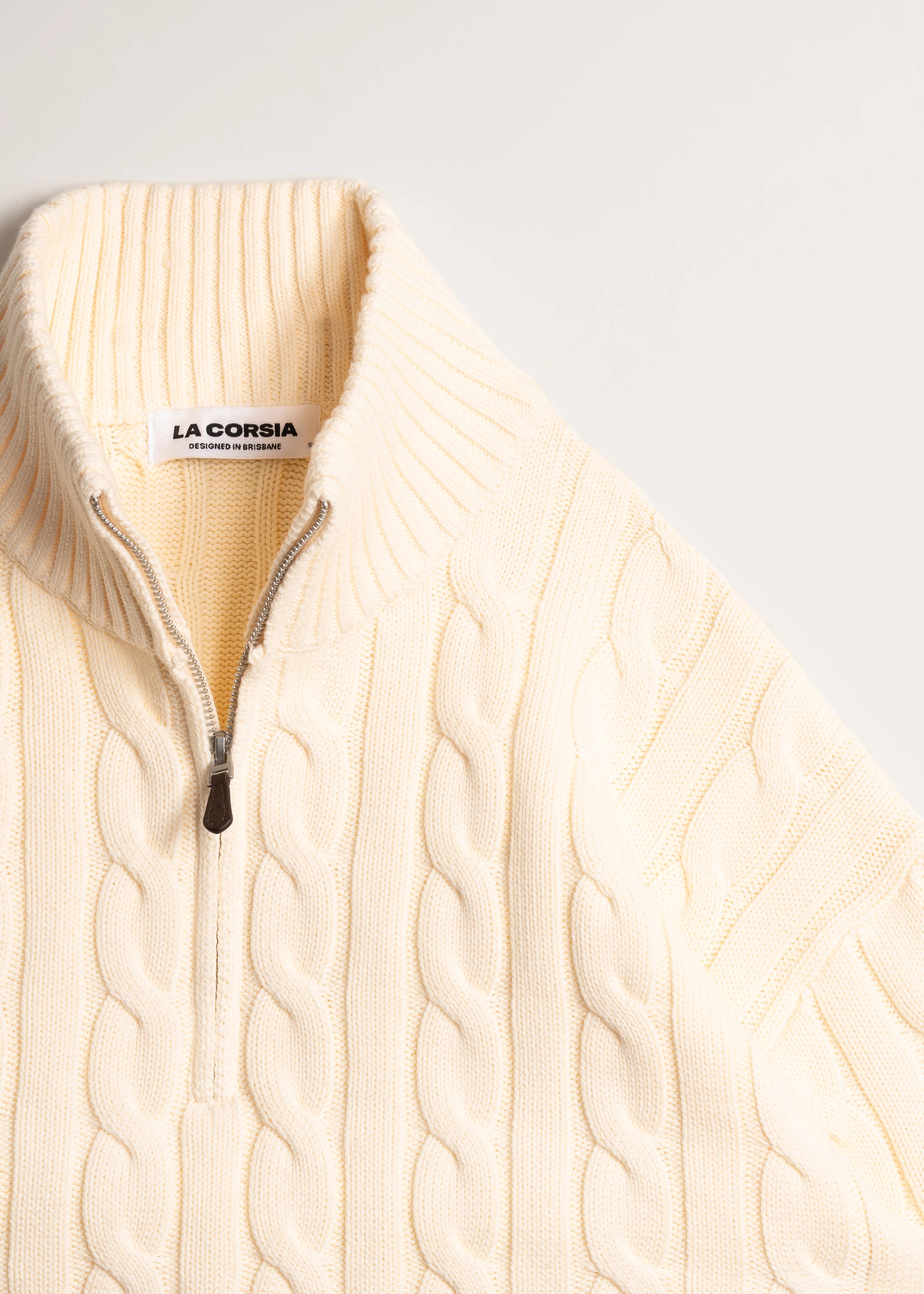 La Corsia Wide Sleeve Cable Knit sweater in cream, crafted from heavyweight cotton with a quarter zip, funnel neck, and sculpted oversized silhouette.