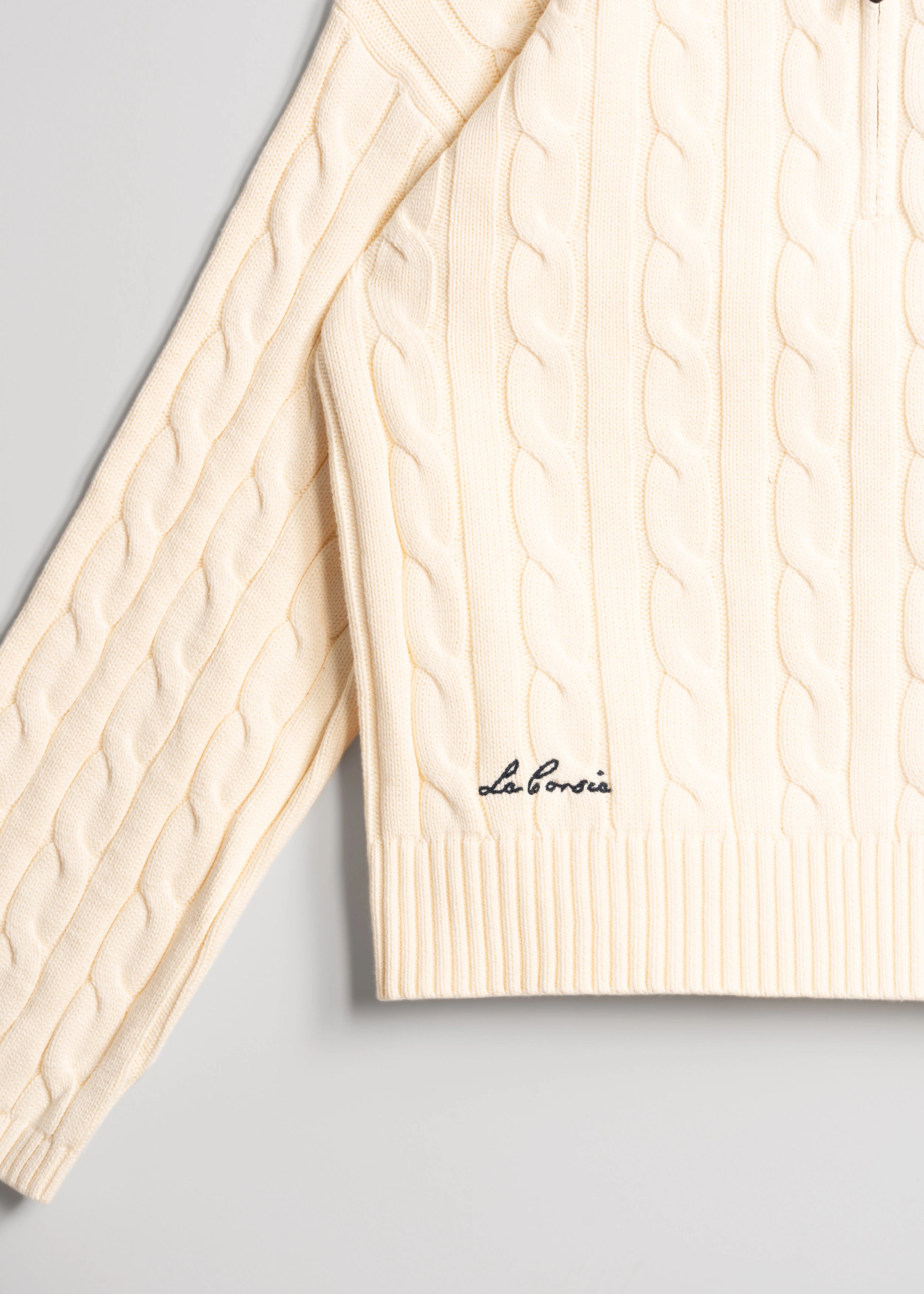 La Corsia Wide Sleeve Cable Knit sweater in cream, crafted from heavyweight cotton with a quarter zip, funnel neck, and sculpted oversized silhouette.