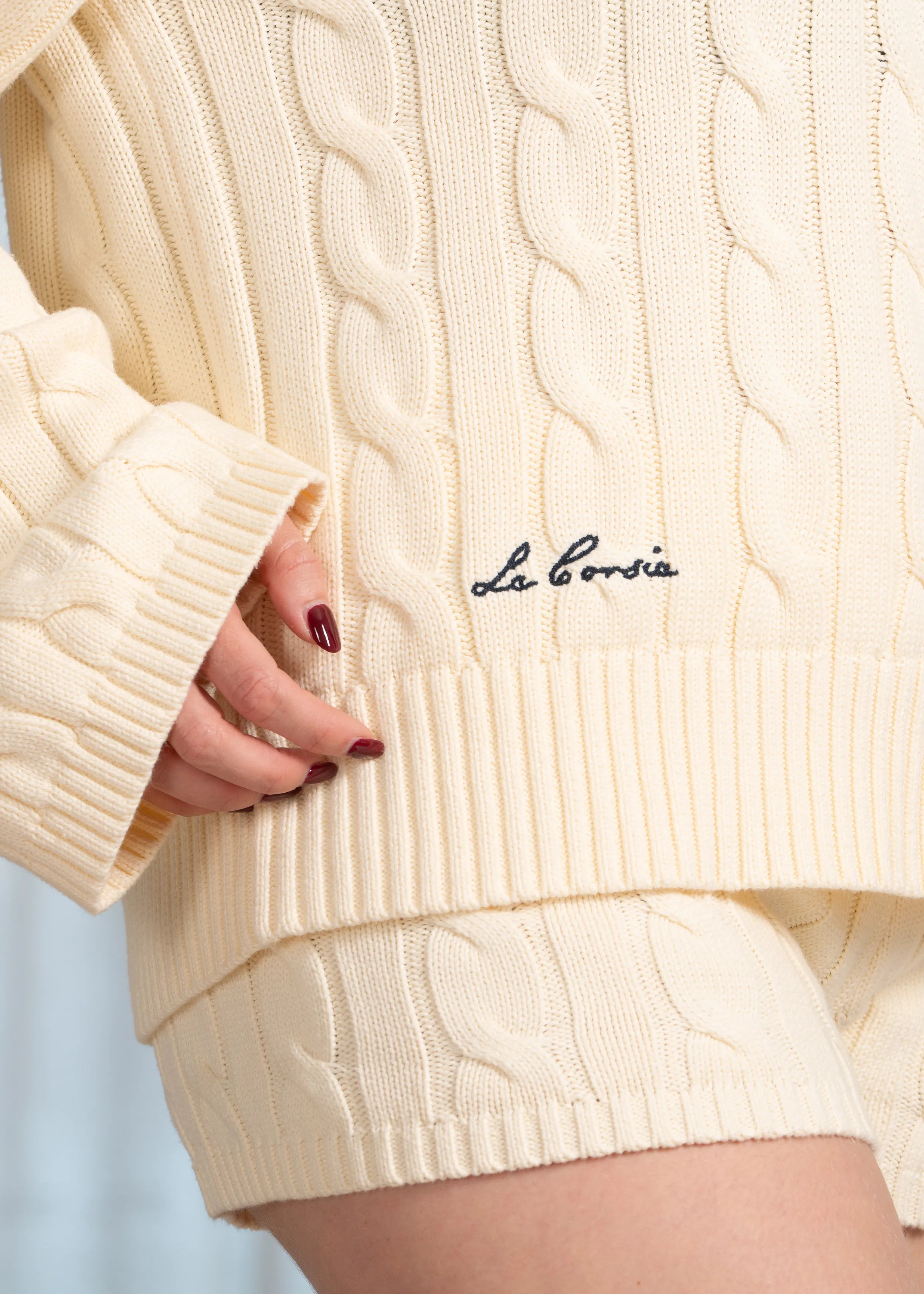 La Corsia Wide Sleeve Cable Knit sweater in cream, crafted from heavyweight cotton with a quarter zip, funnel neck, and sculpted oversized silhouette.