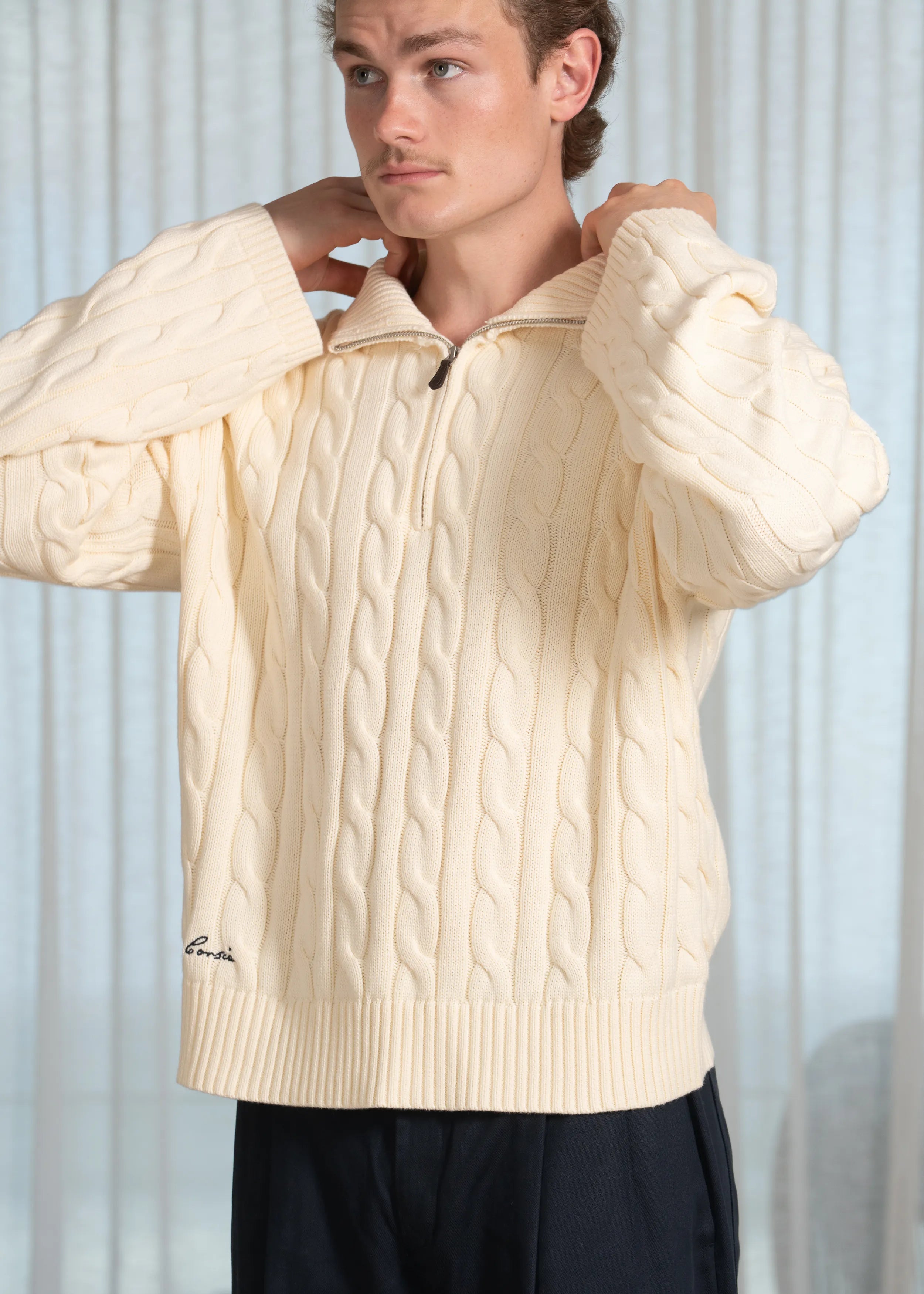 La Corsia Wide Sleeve Cable Knit sweater in cream, crafted from heavyweight cotton with a quarter zip, funnel neck, and sculpted oversized silhouette.