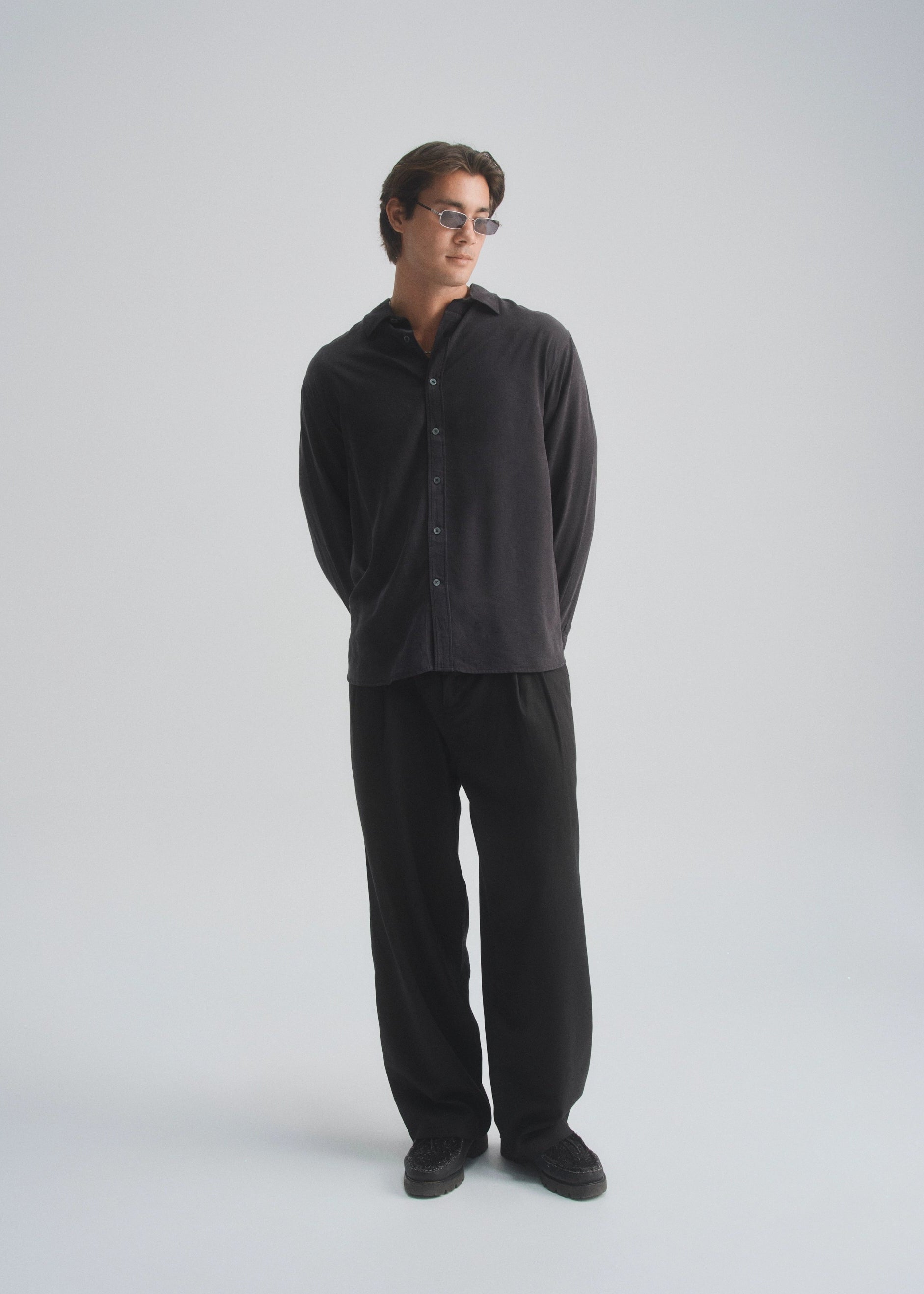 Person wearing a black shirt and pants on a white background