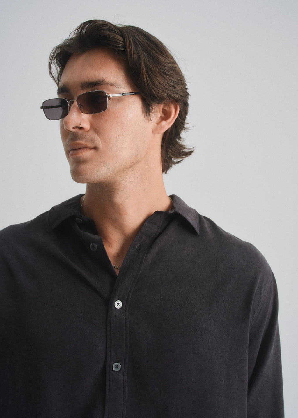 Man wearing a black shirt and sunglasses against a plain background