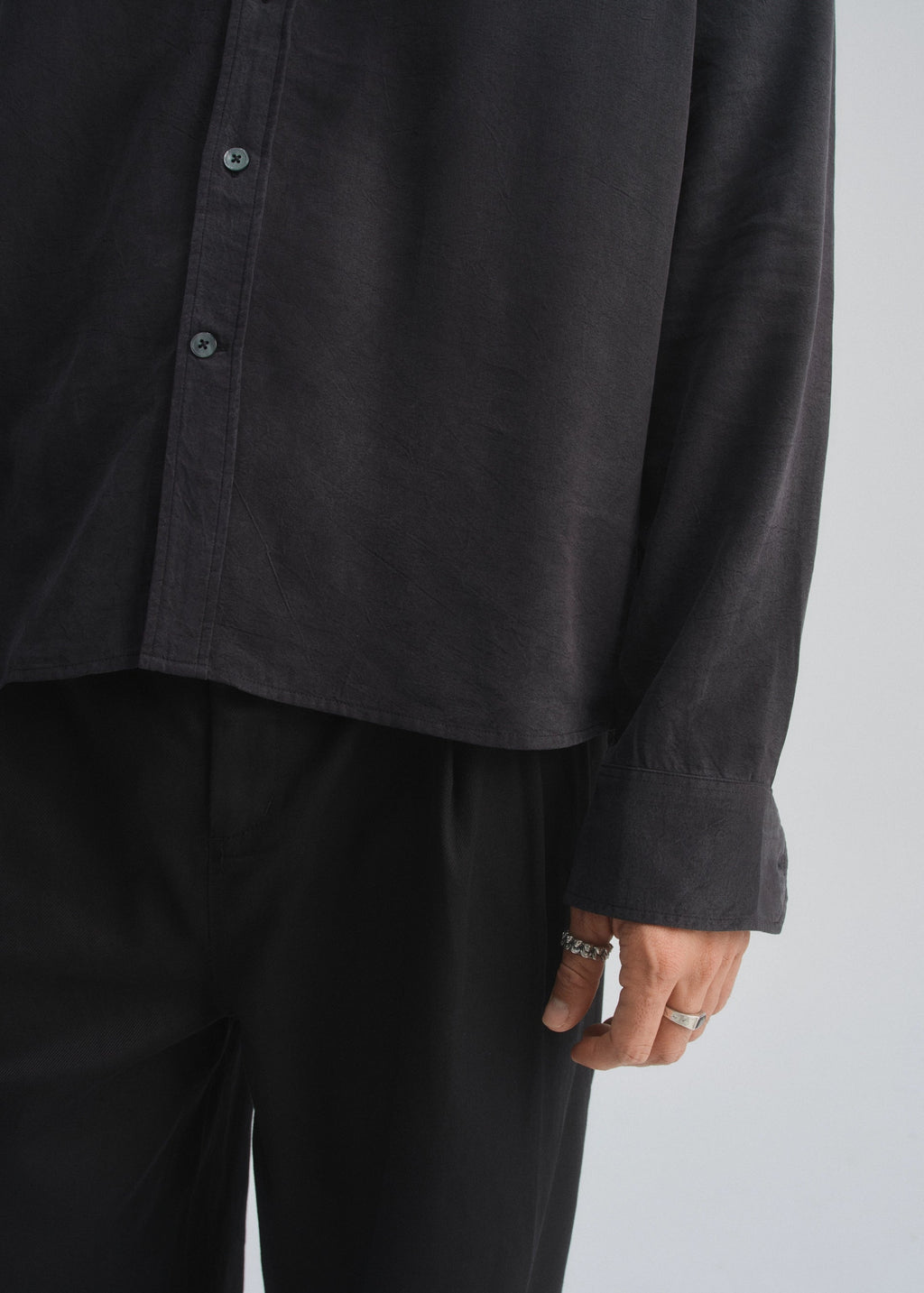 Person wearing a black button-up shirt and pants on a plain background