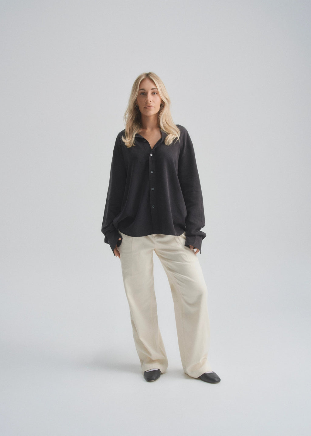 Woman wearing a black shirt and beige pants on a white background