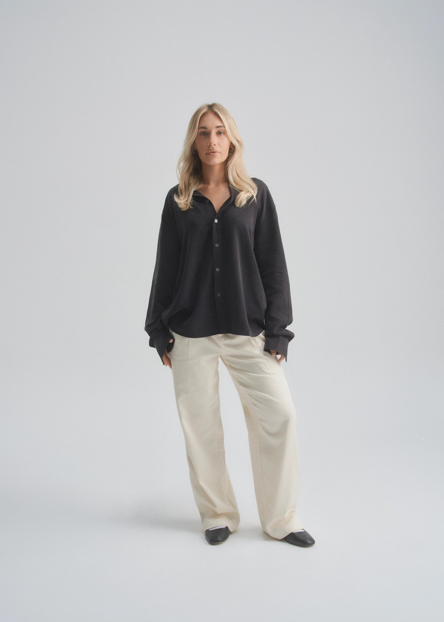 Woman wearing a black shirt and beige pants on a white background