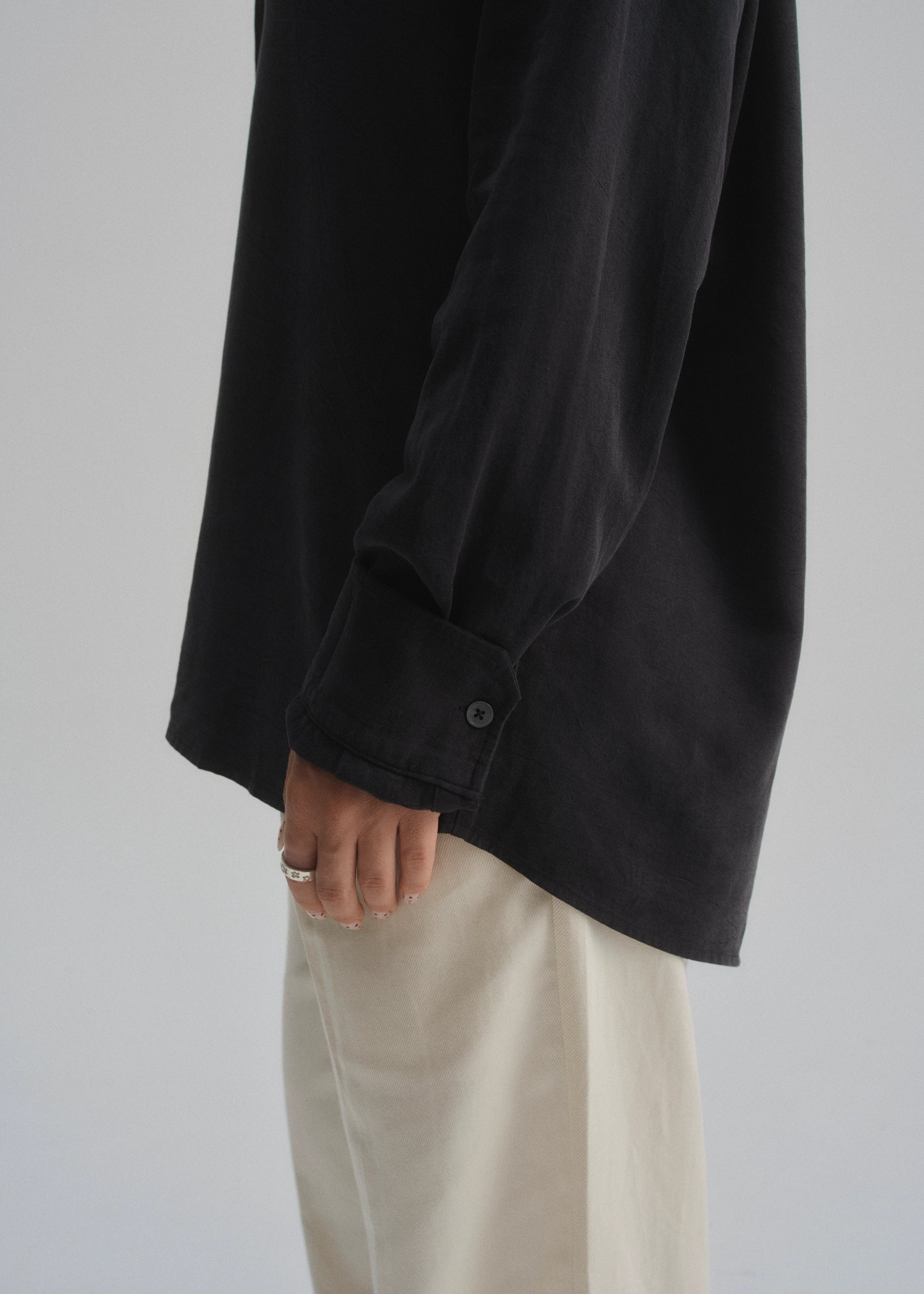 Person wearing a black shirt and beige pants on a plain background