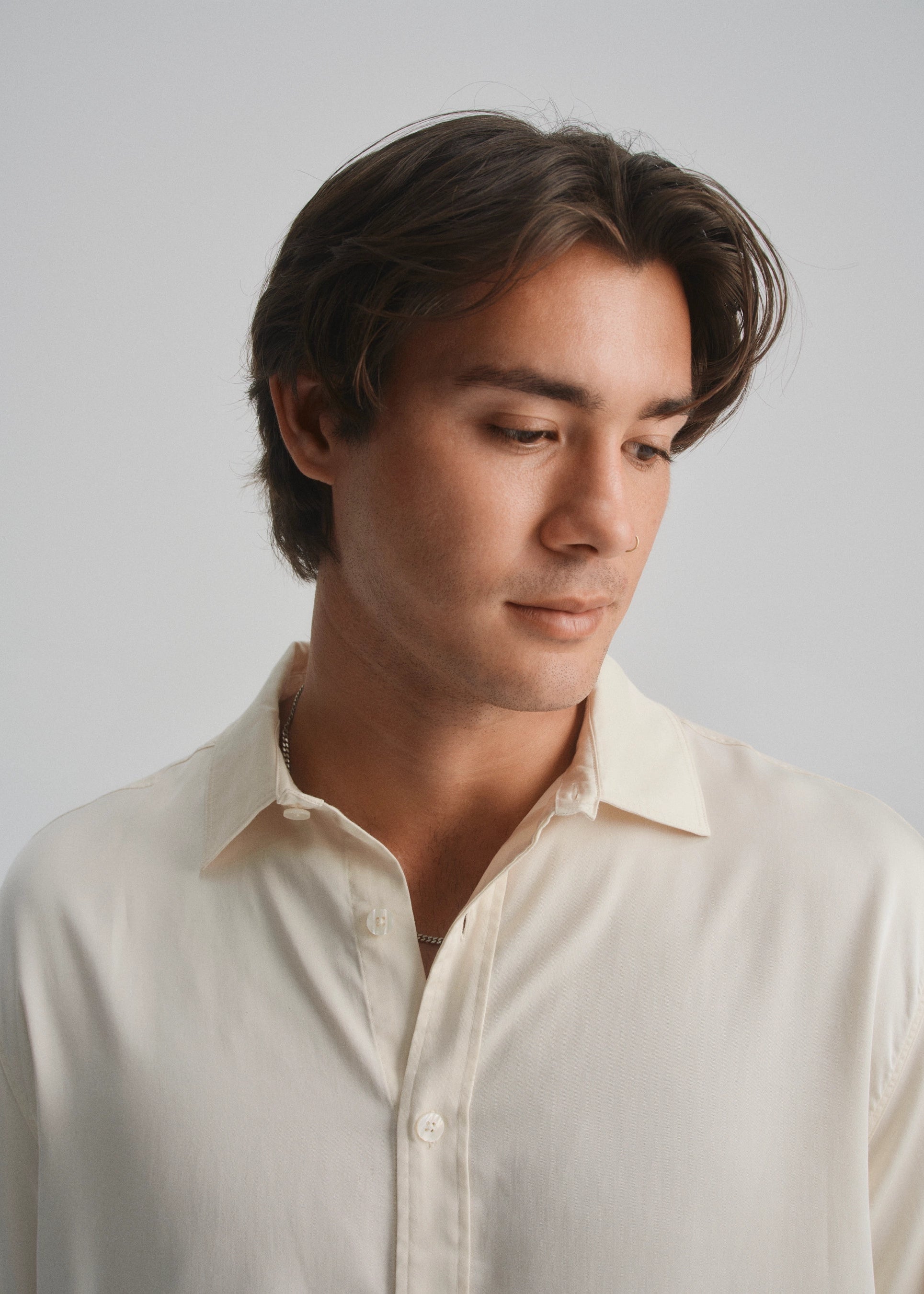 Man wearing a light-cream colored shirt against a plain background