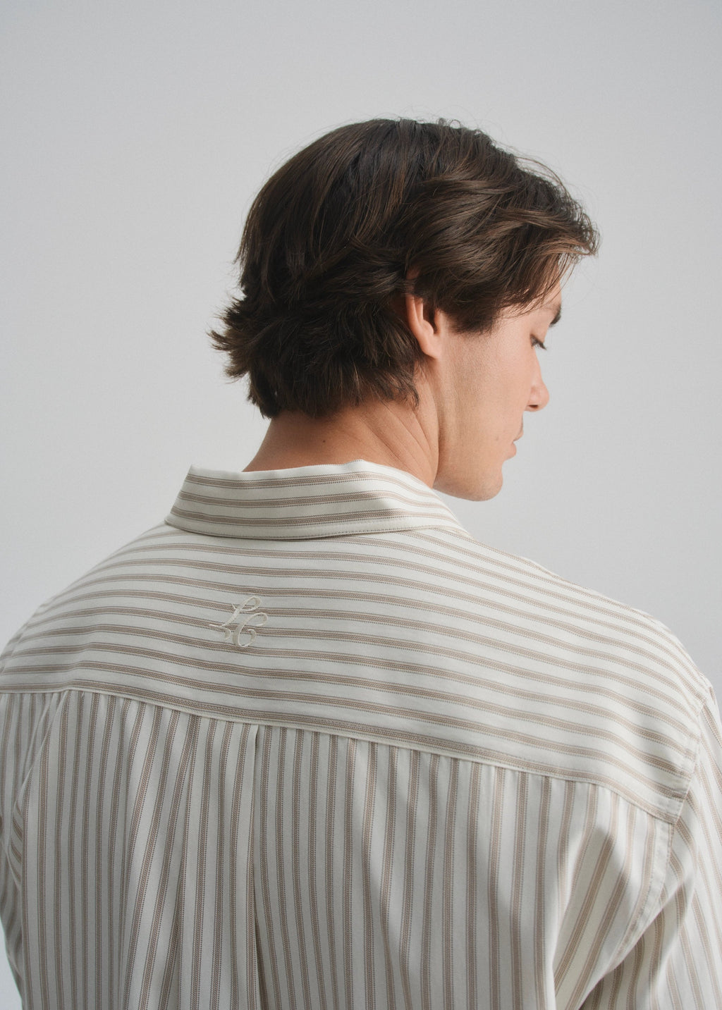 Person wearing a striped cream & brown shirt against a plain background