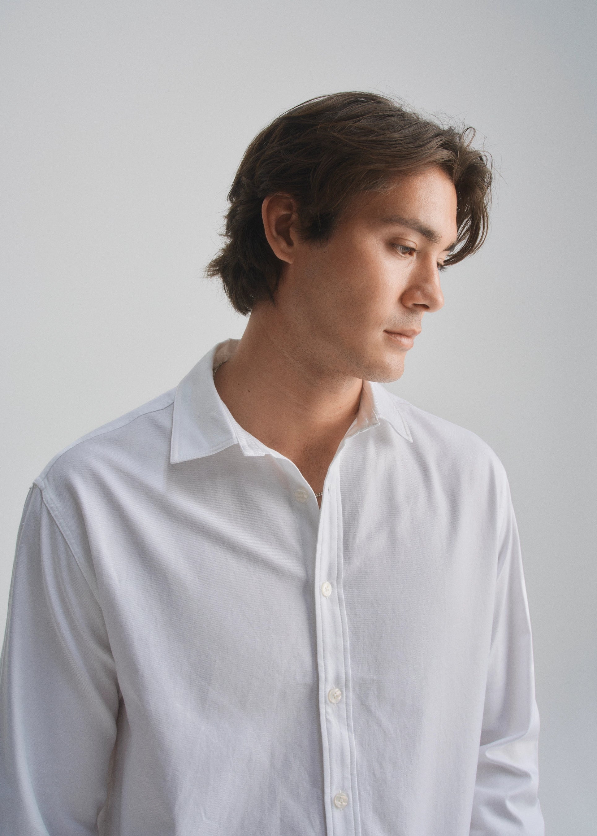 Man wearing a white shirt against a plain background