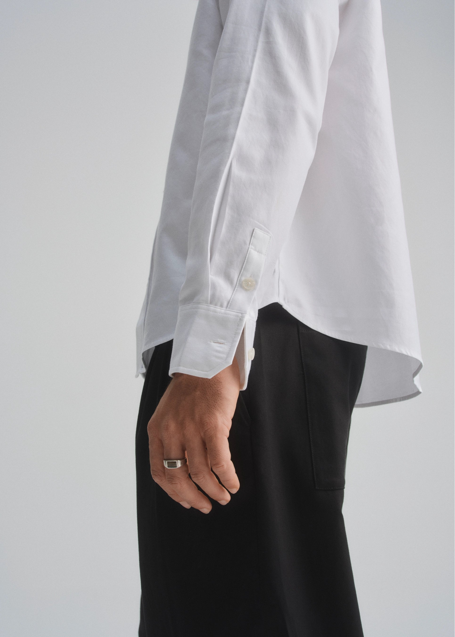 White shirt with unbuttoned sleeves and black pants on a plain background