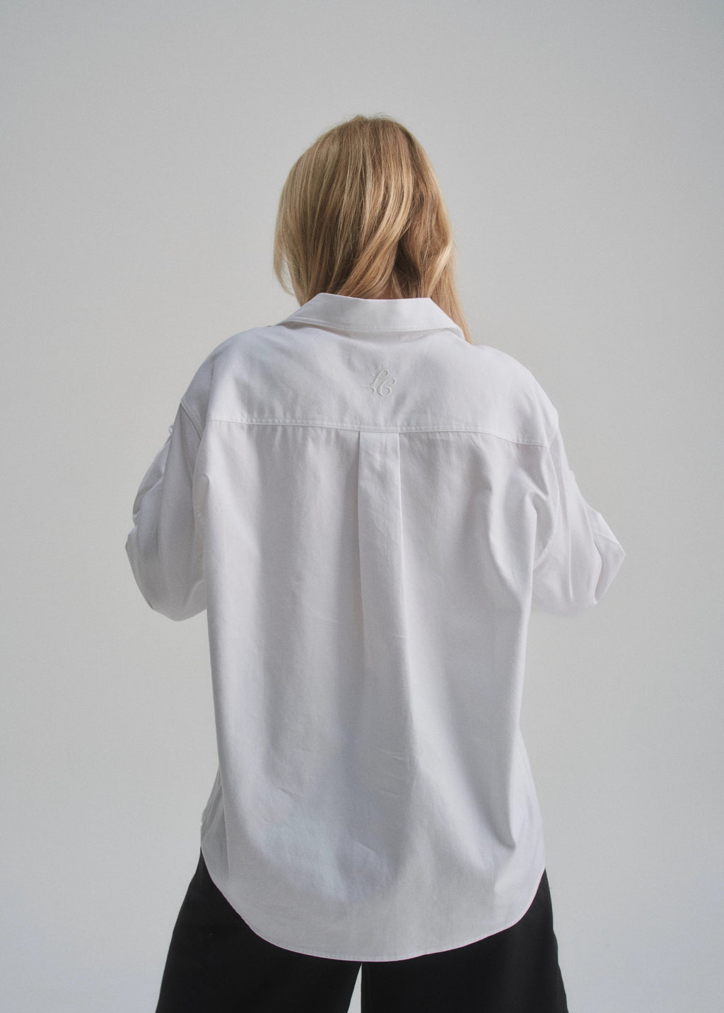 Person wearing a white shirt against a plain background