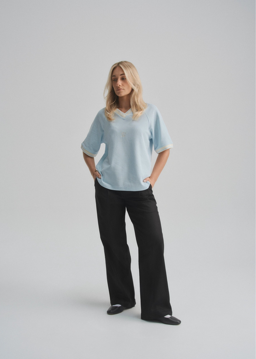 Person wearing a light blue polo jersey and black pants on a plain background