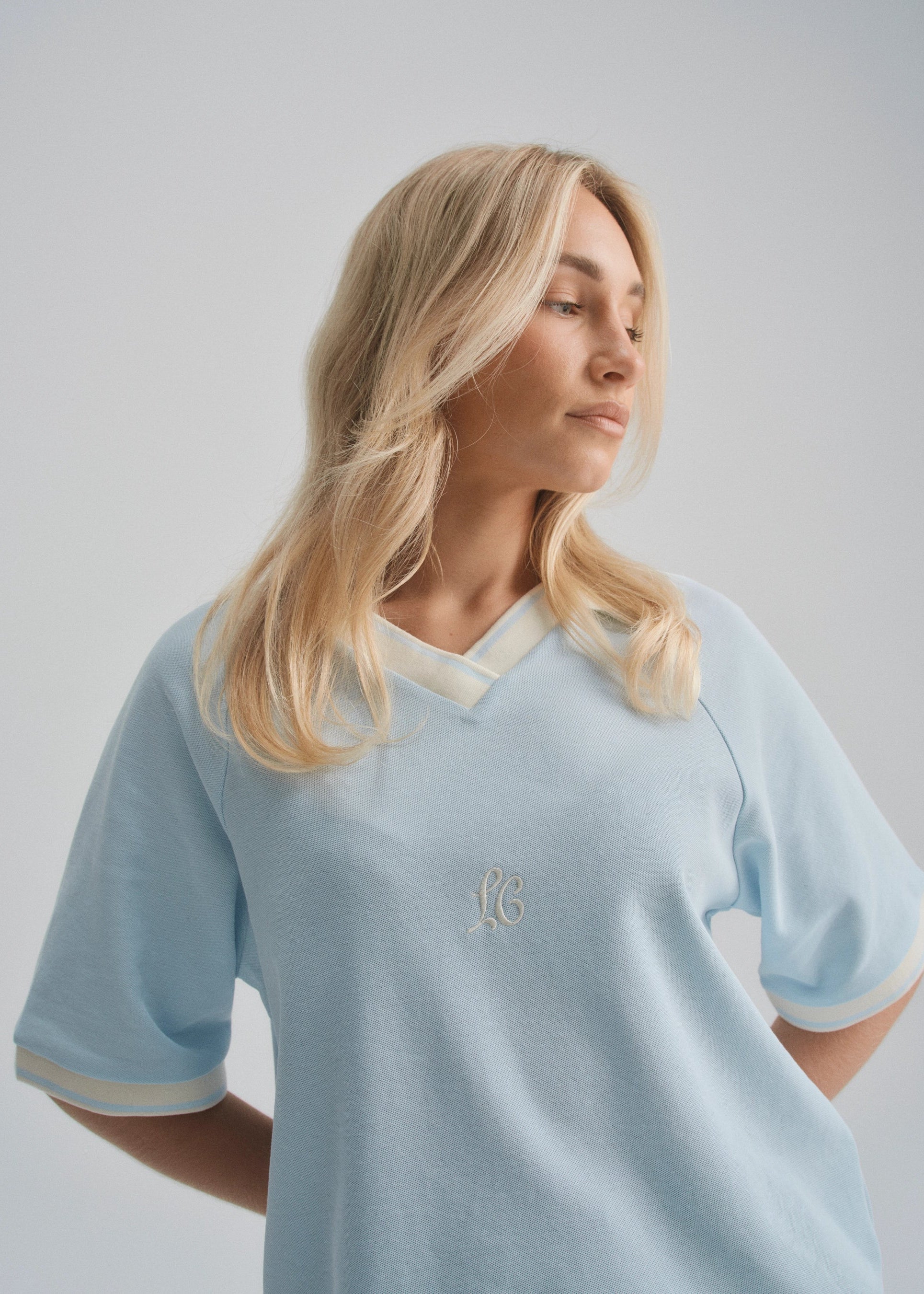 Woman wearing a light blue jersey with a logo on a plain background