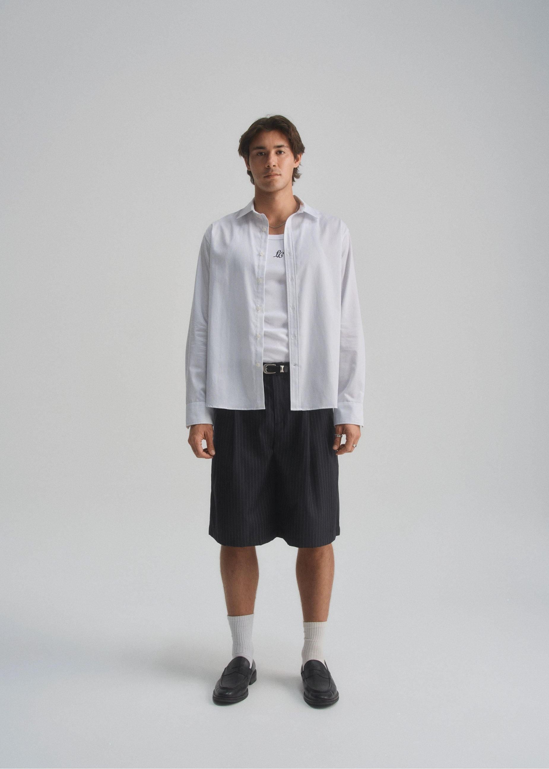 Person wearing a white shirt and black shorts on a gray background