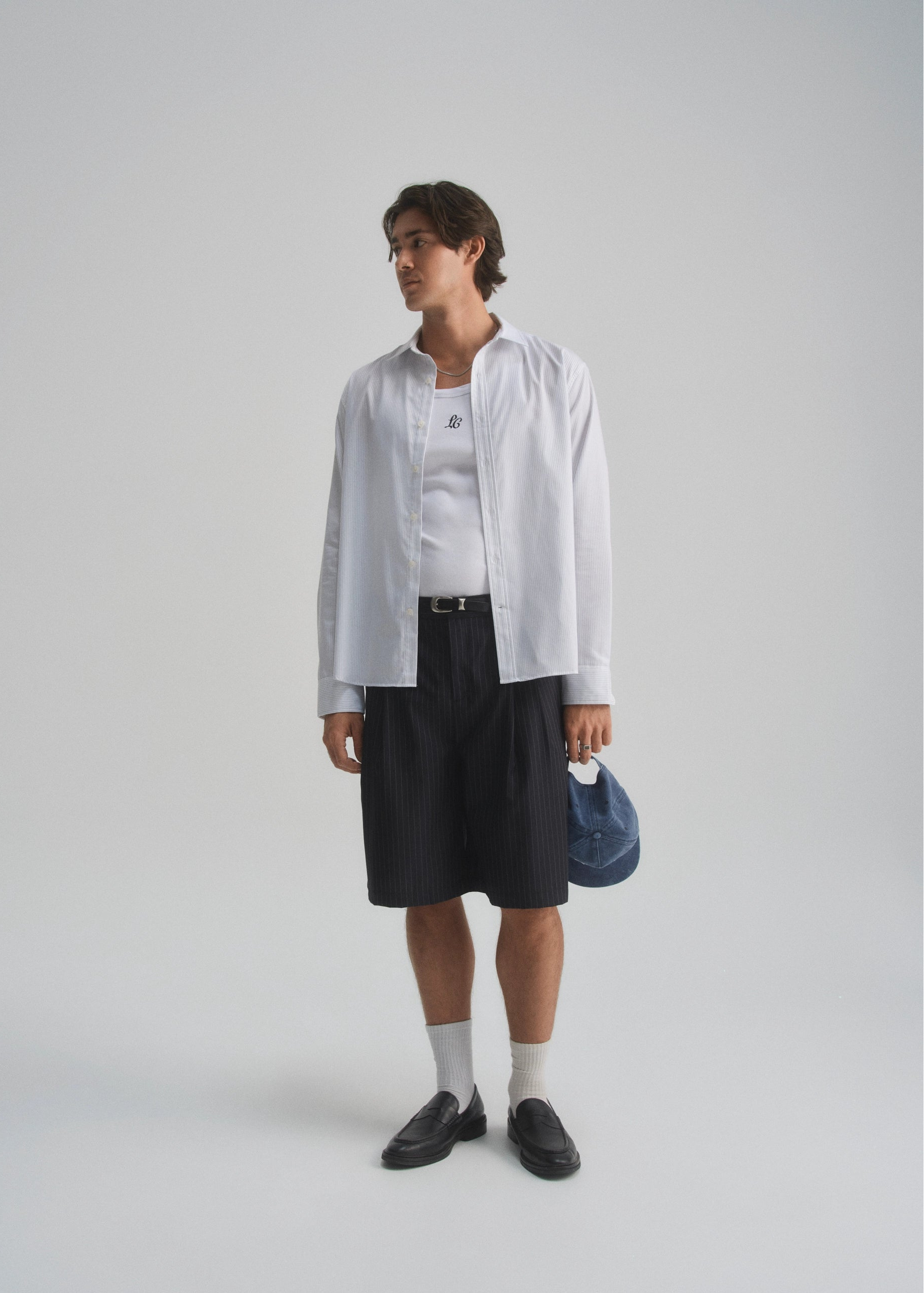 Person wearing a white shirt and black shorts on a plain background