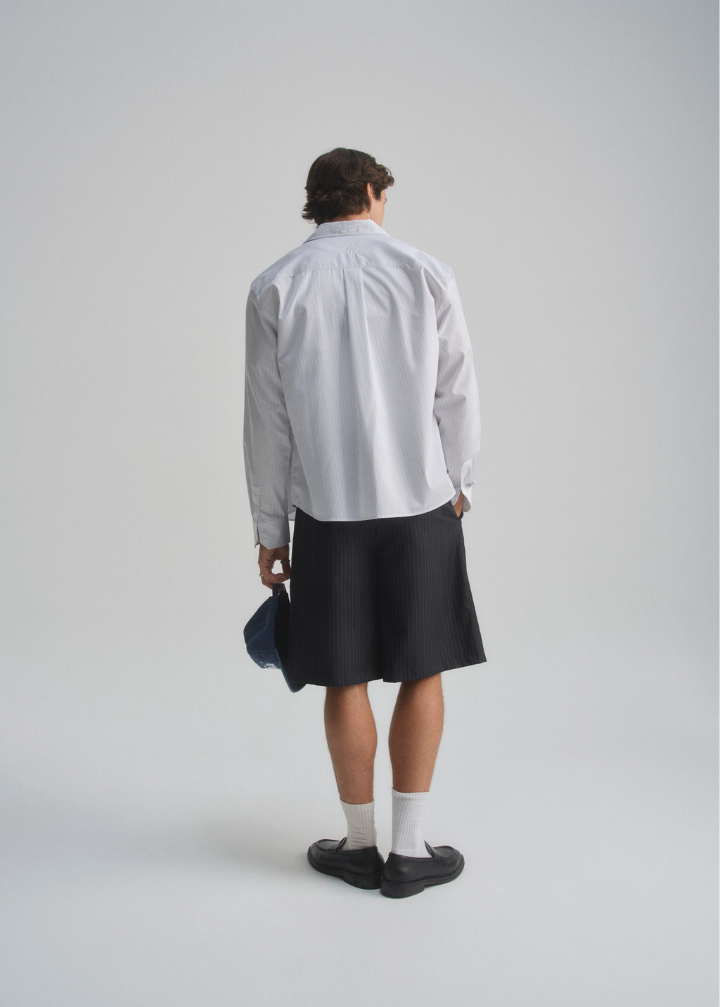 Person wearing a light gray shirt and black skirt on a plain background