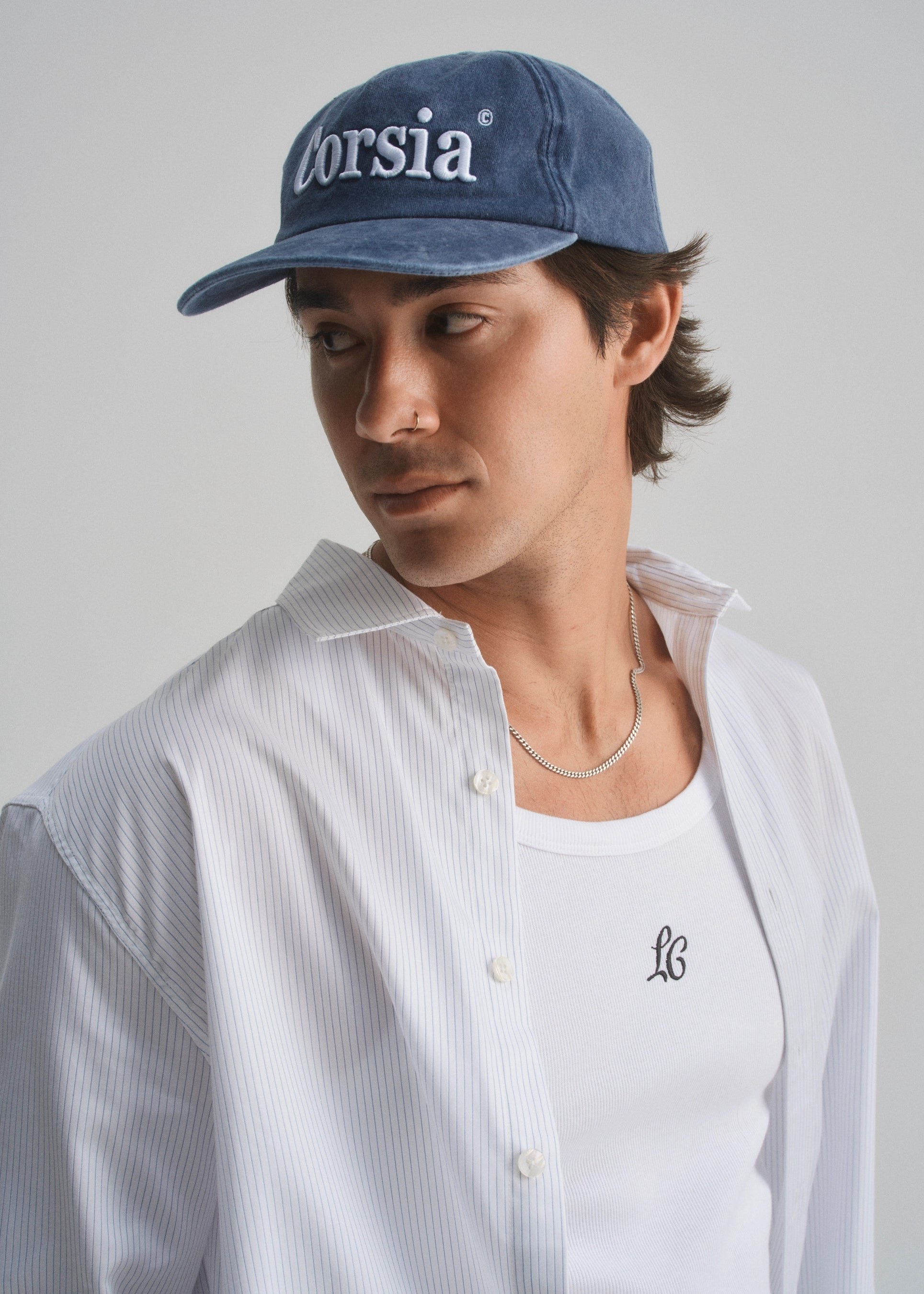 Person wearing a blue cap with 'corsia' branding and a white shirt with a logo.