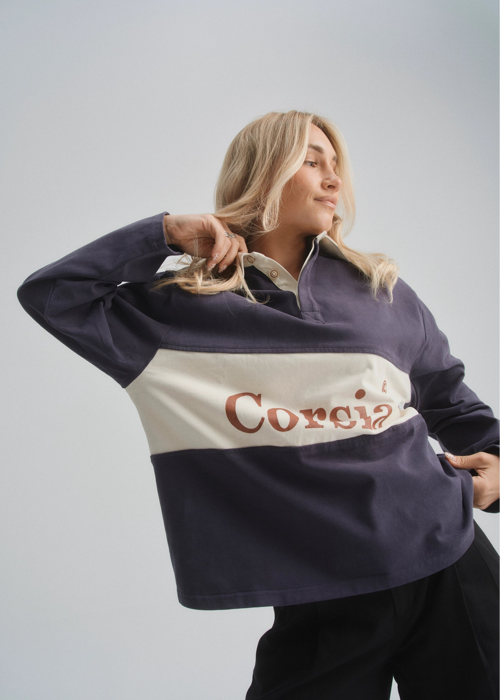 Person wearing a navy and white rugby-style shirt with 'Corsia' text on a plain background