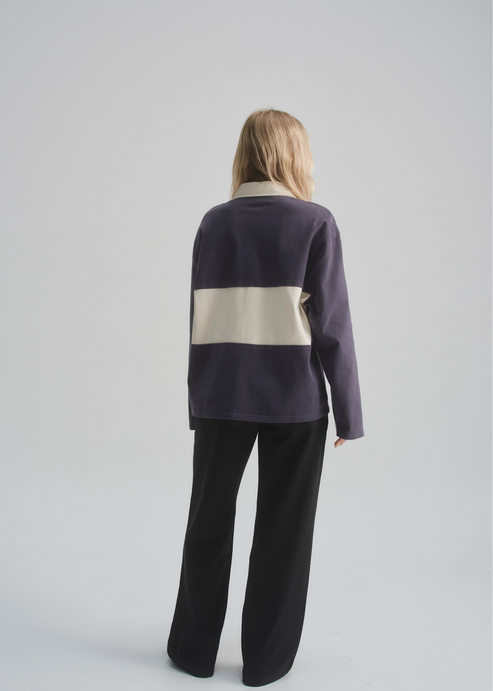 Person wearing a two-tone sweater with a white and faded navy design on a plain background