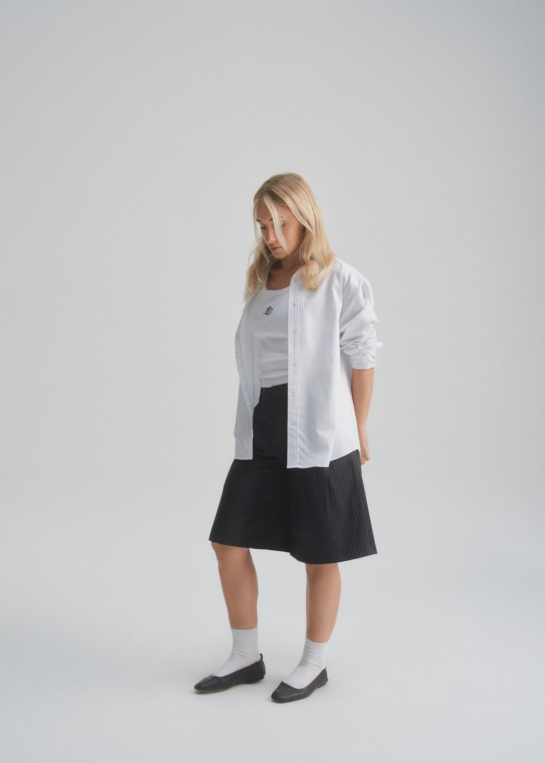 Woman wearing a white shirt and black skirt on a plain background