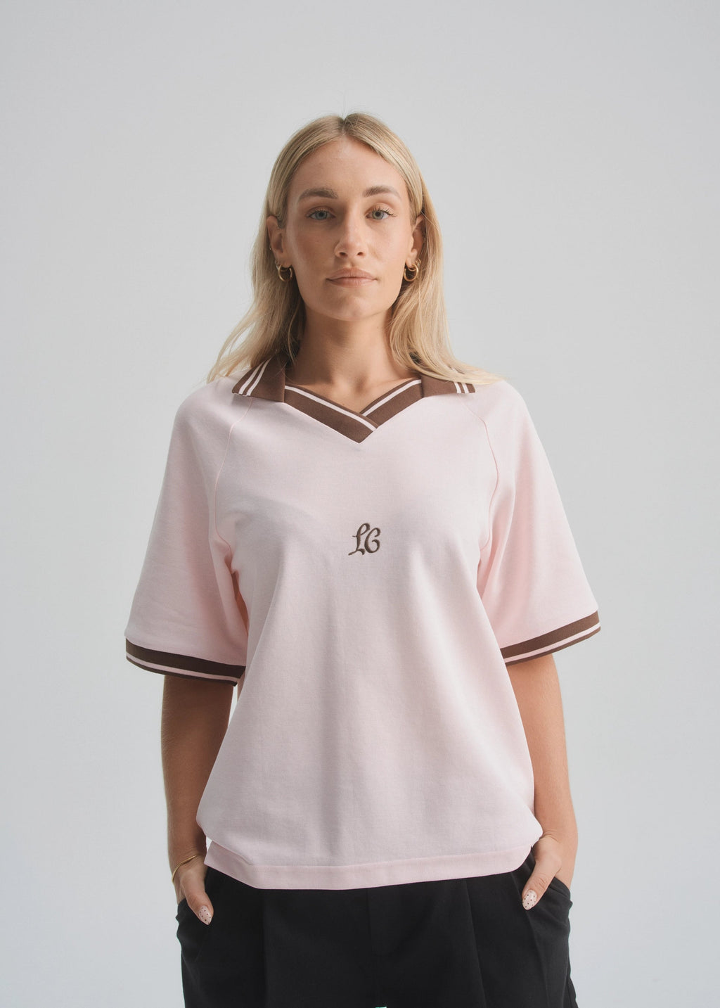 Woman wearing a light pink jersey with a logo on a plain background