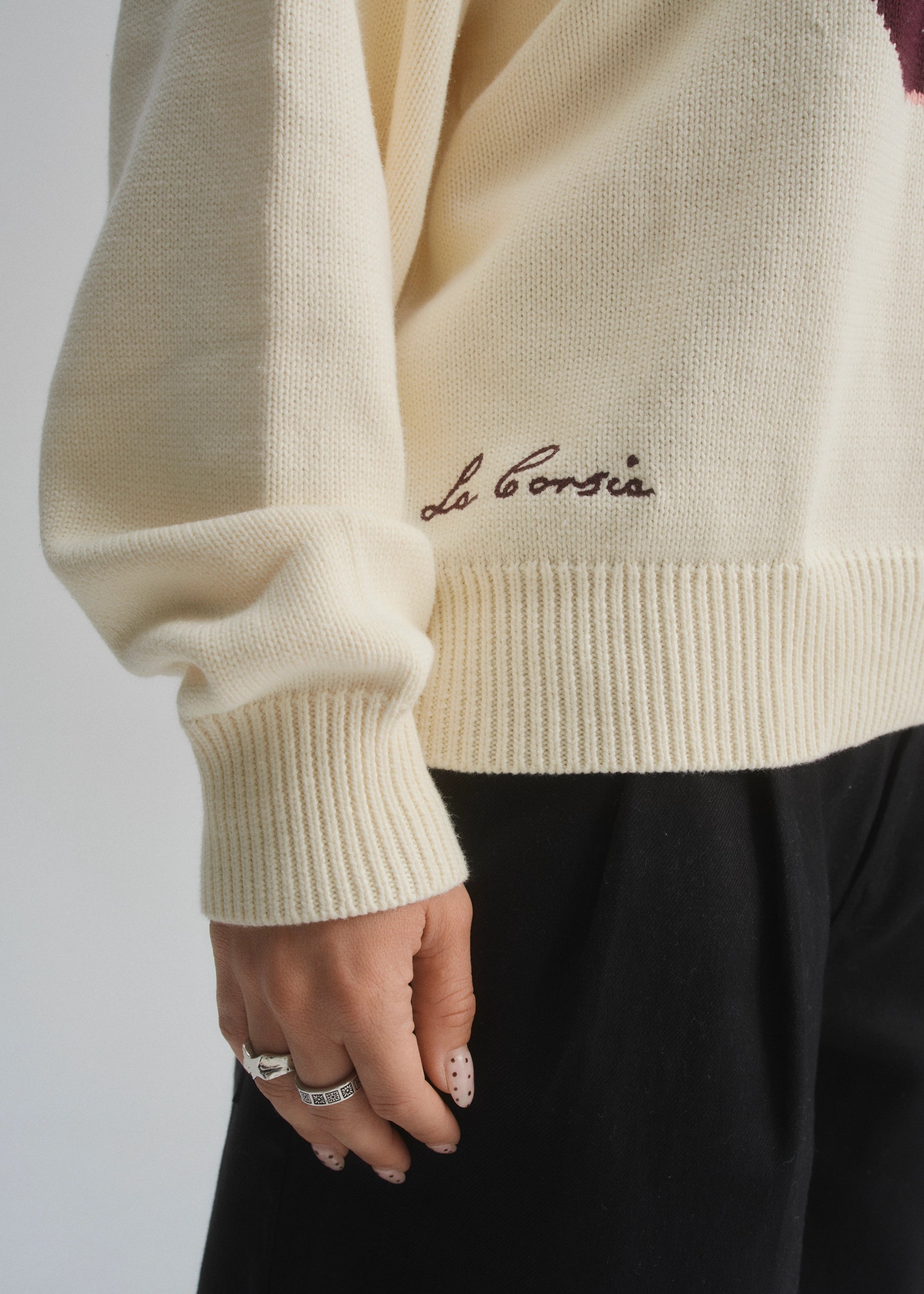 Beige sweater with 'La Corsia' chainstitched embroidery on a plain background