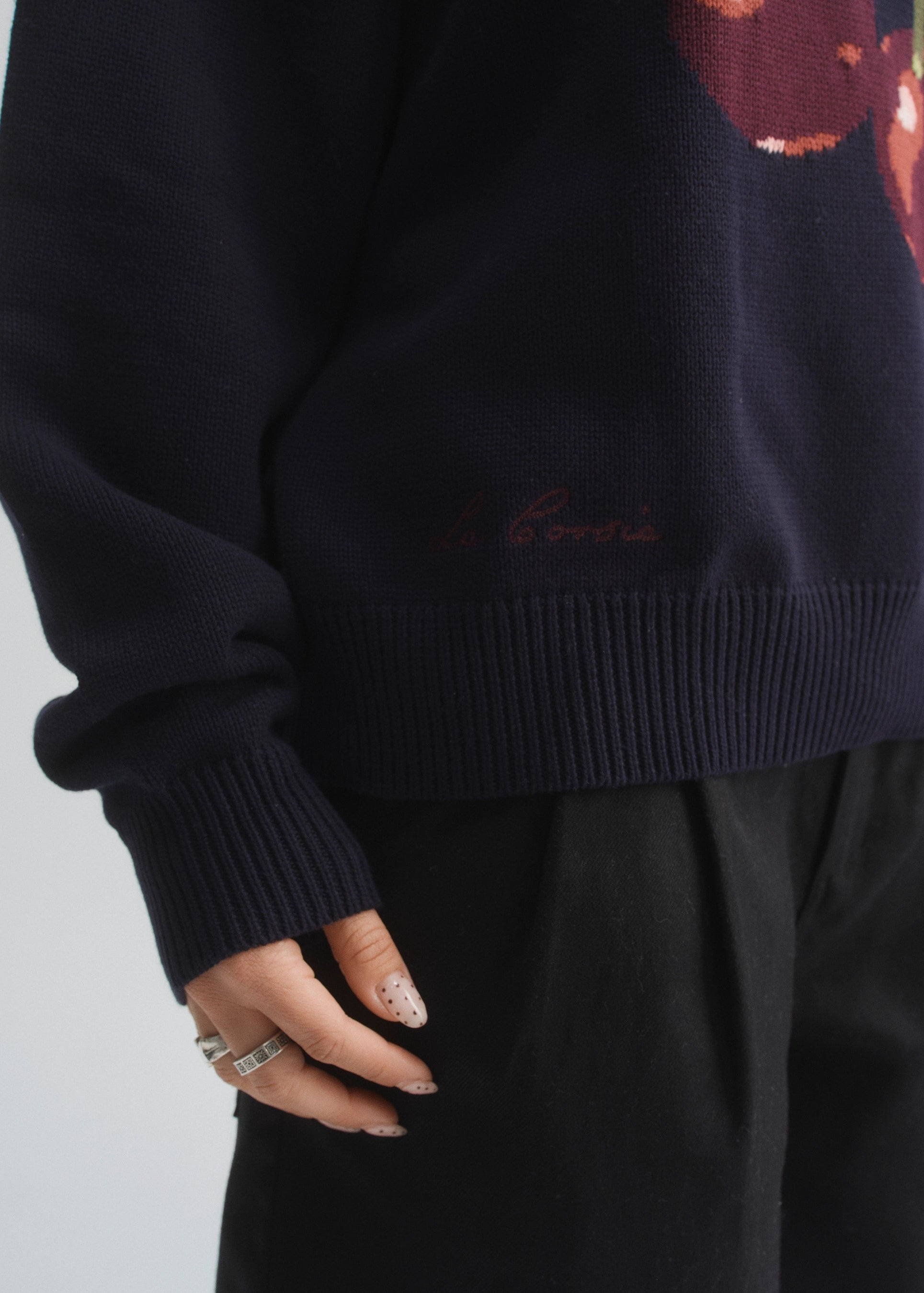 Person wearing a dark navy sweater with a cherry patterns on a light gray background