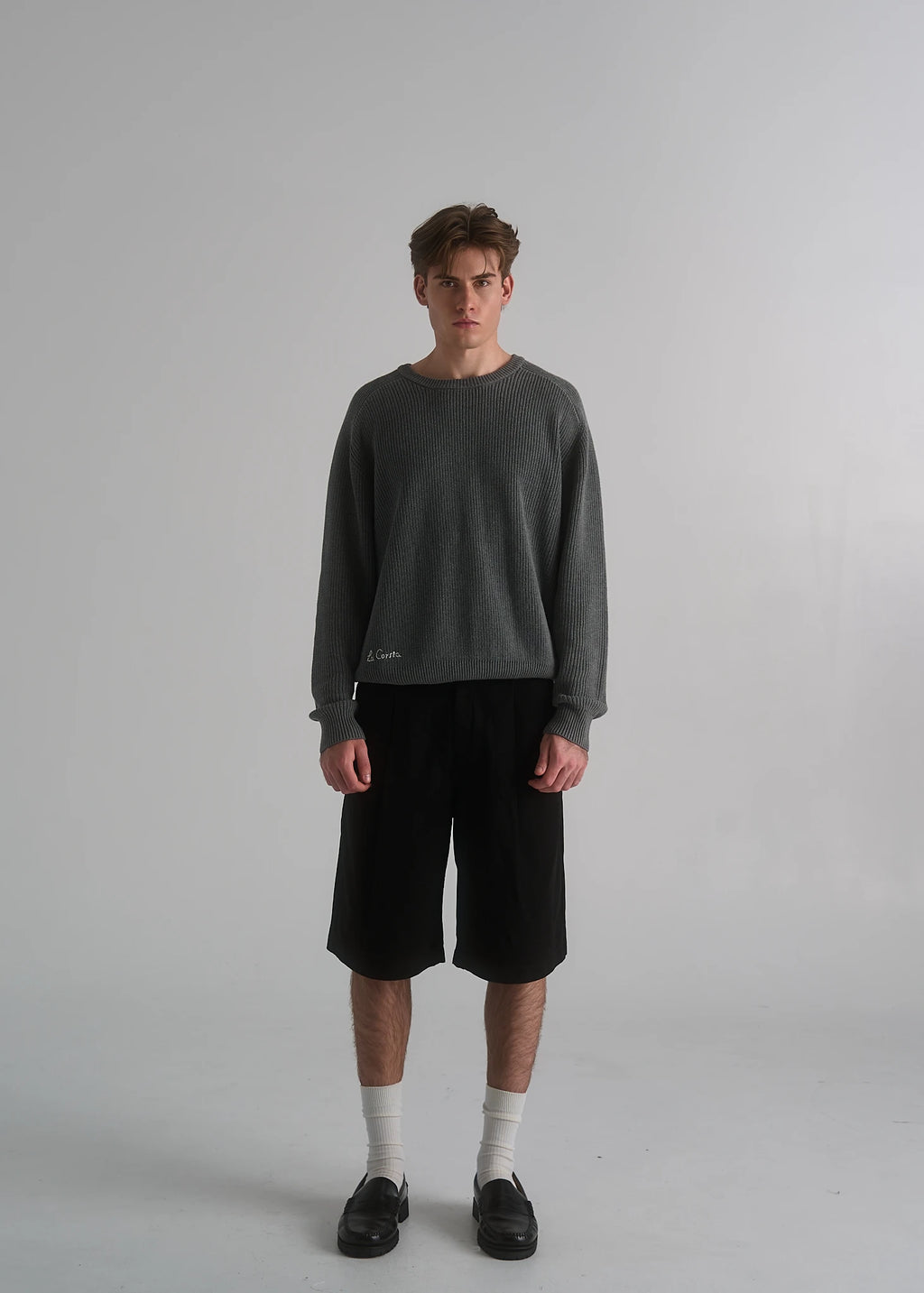 La Corsia Cotton Fisherman Sweater in grey marle worn by a model on a plain studio background