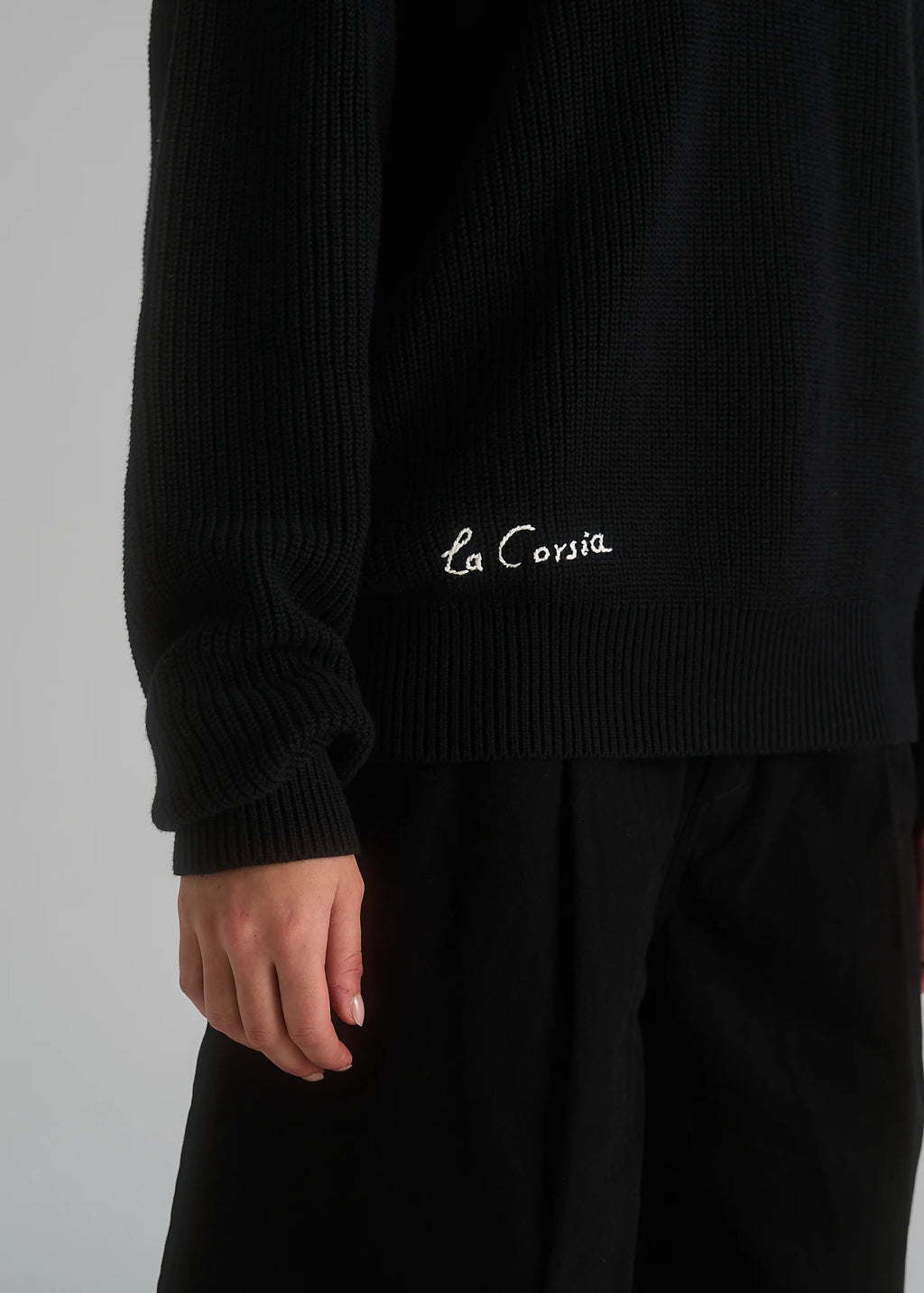 La Corsia Cotton Fisherman Sweater in black worn by a model on a plain studio background
