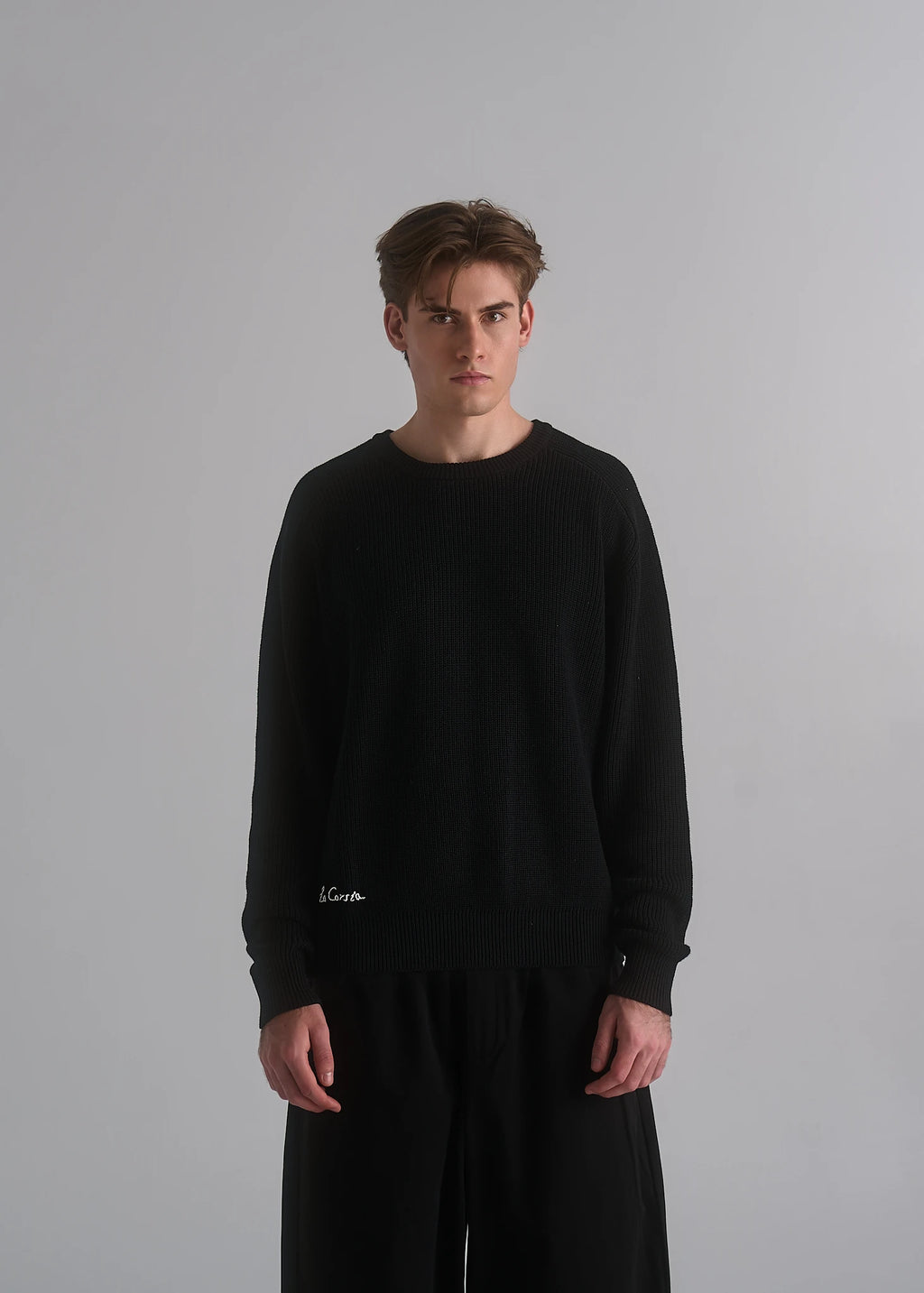 La Corsia Cotton Fisherman Sweater in black worn by a model on a plain studio background