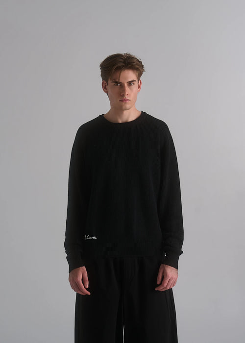 La Corsia Cotton Fisherman Sweater in black worn by a model on a plain studio background