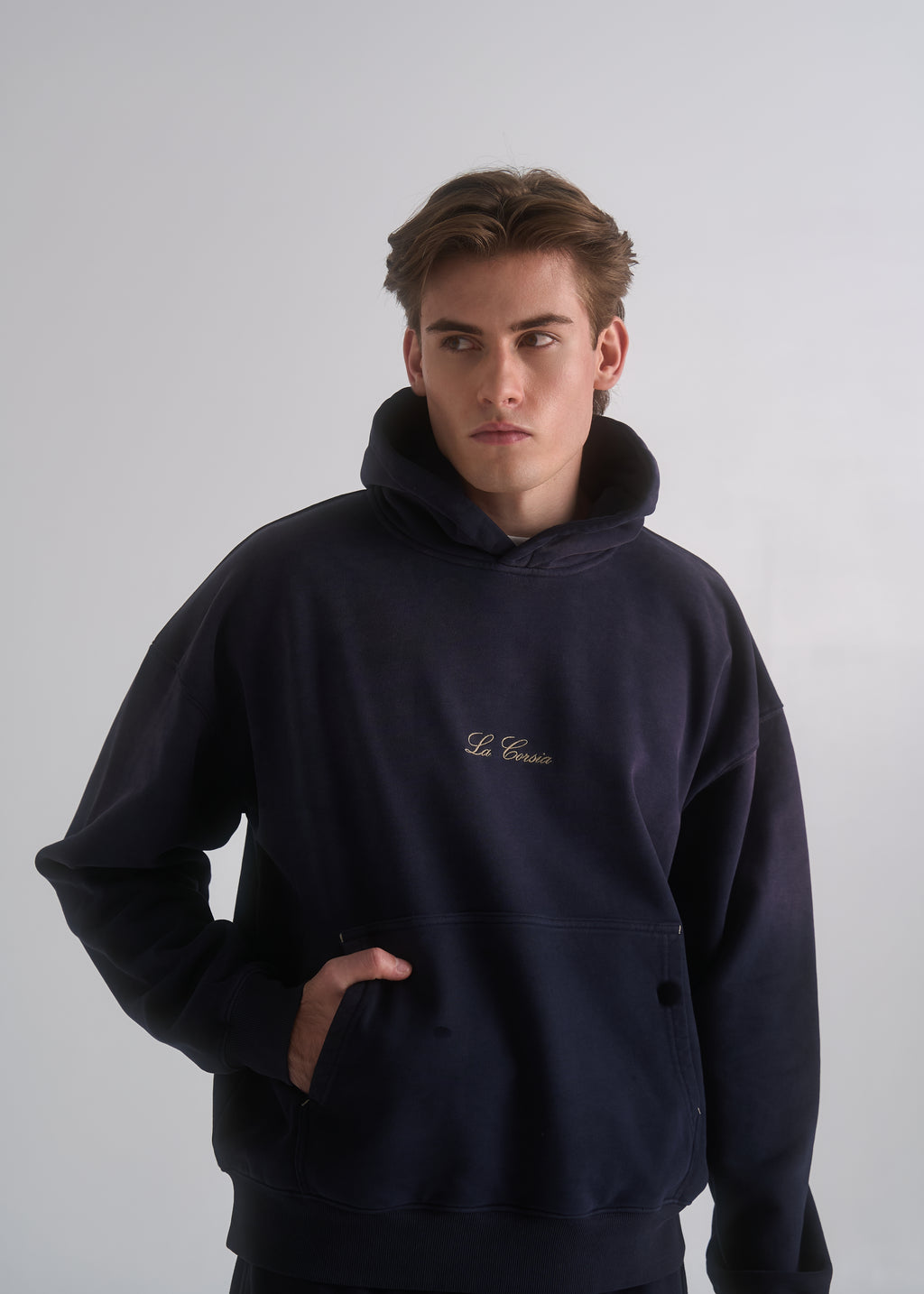 La Corsia Washed Script Hoodie in washed navy worn by a model on a plain studio background