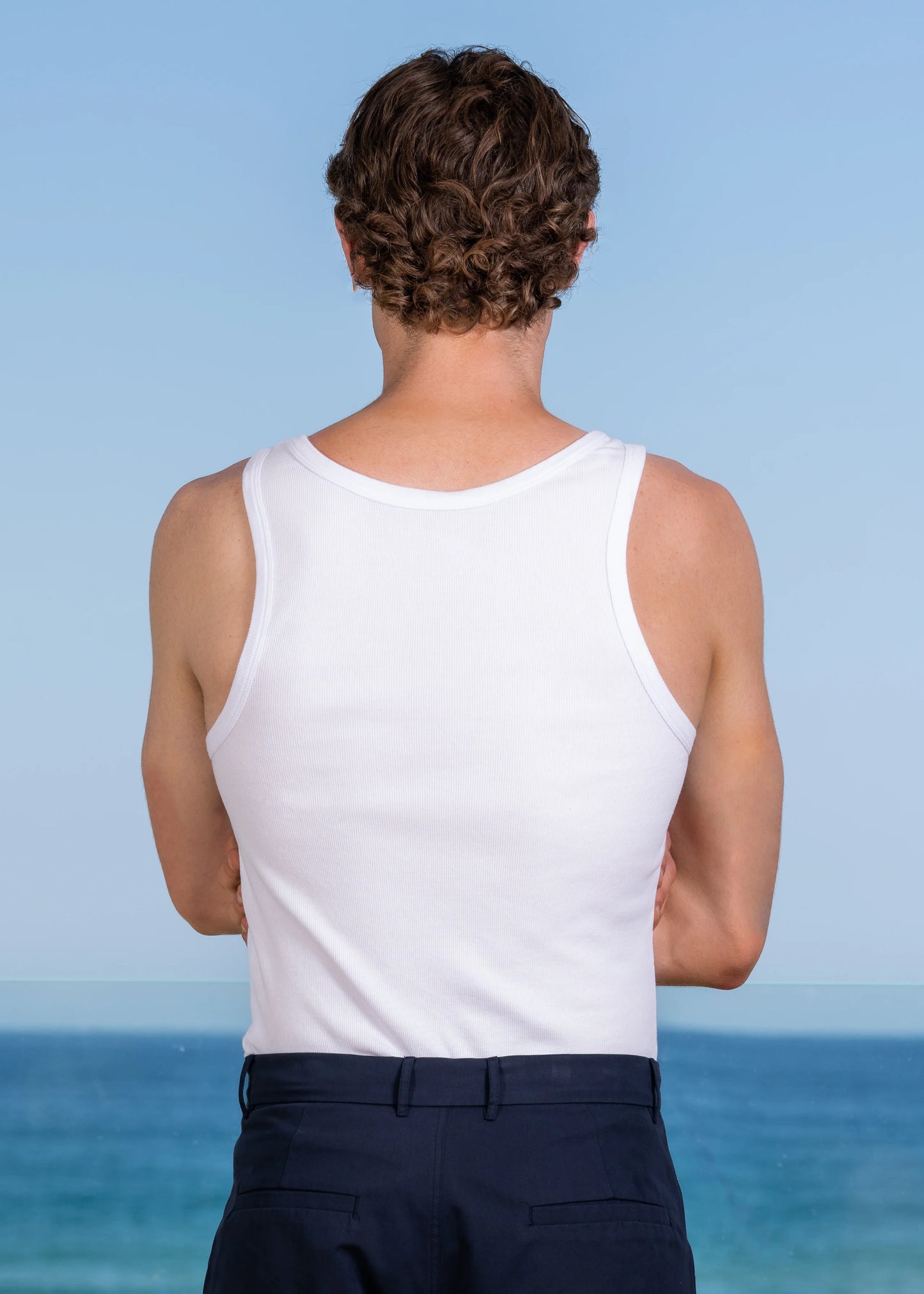 Close-up of model wearing LC monogram embroidered ribbed tank top, scooped neckline.