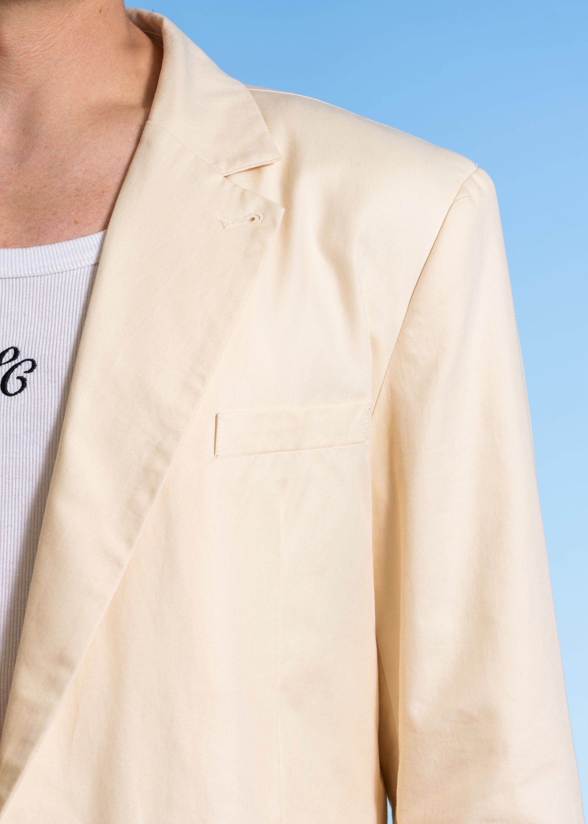 Closeup photography showing shoulder structure, barchetta pocket, and machine button hole on lapel. Double breasted jacket.