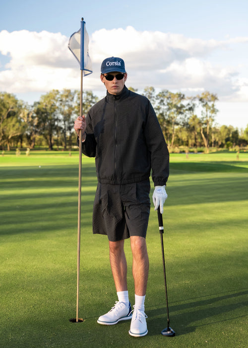 Man in golf attire on a golf course holding a flagstick.