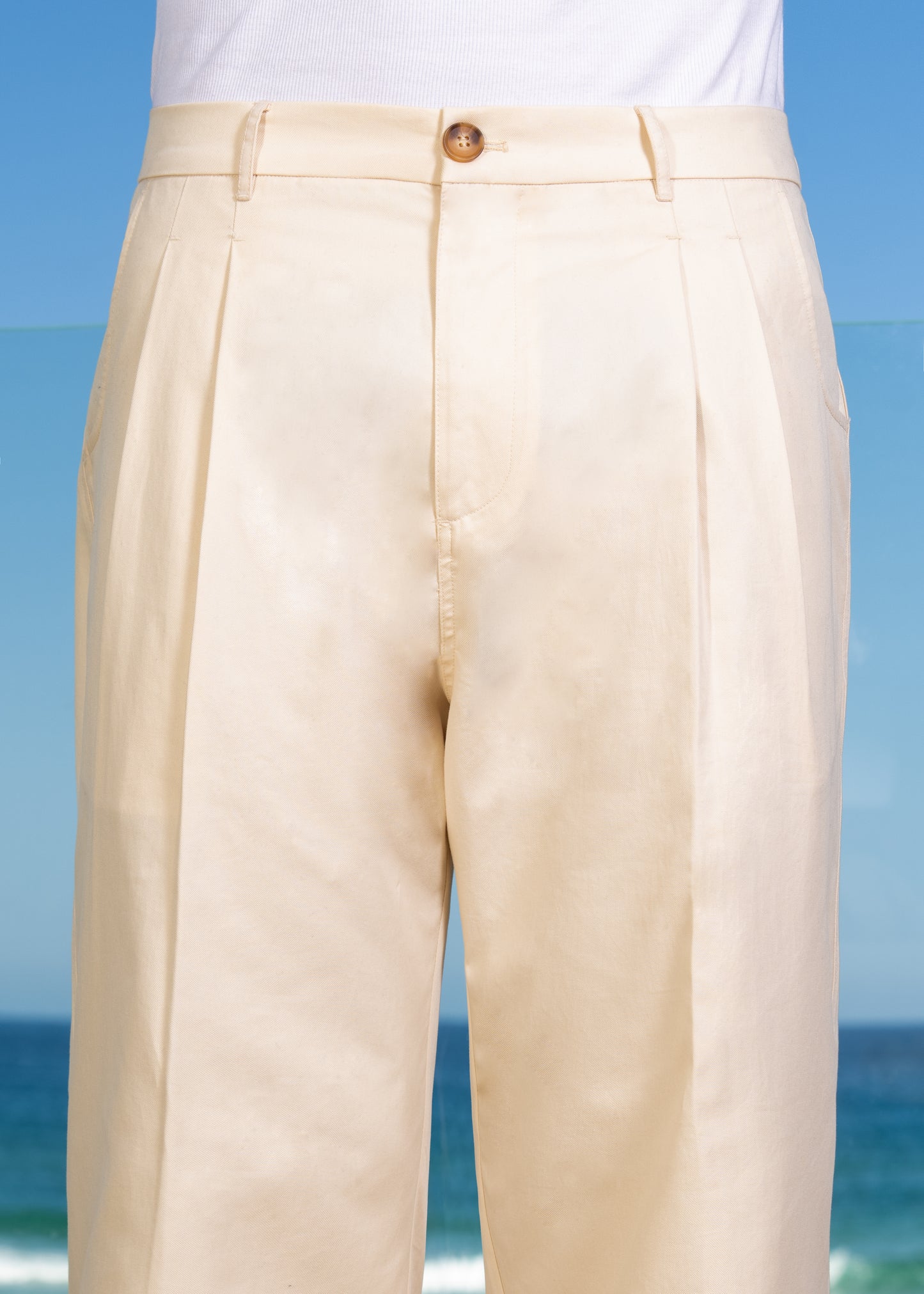 Detailed front double pleats and zipper fly. Horn button front closure. Loose fit Cream Pleated Pant.