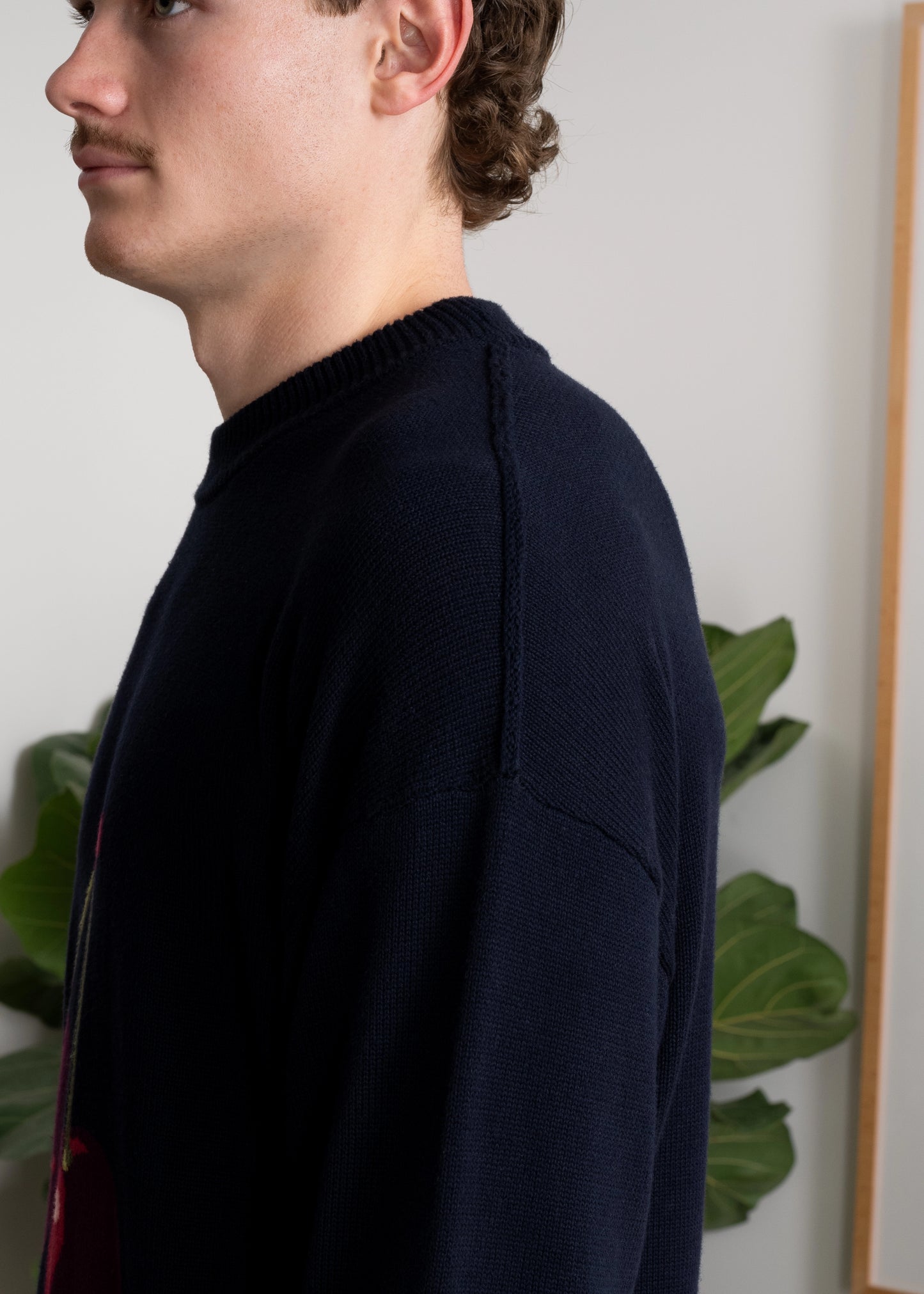 Closeup shoulder details of Cherry Intarsia Knit on model. Exposed drop shoulder seam. Loose fit.