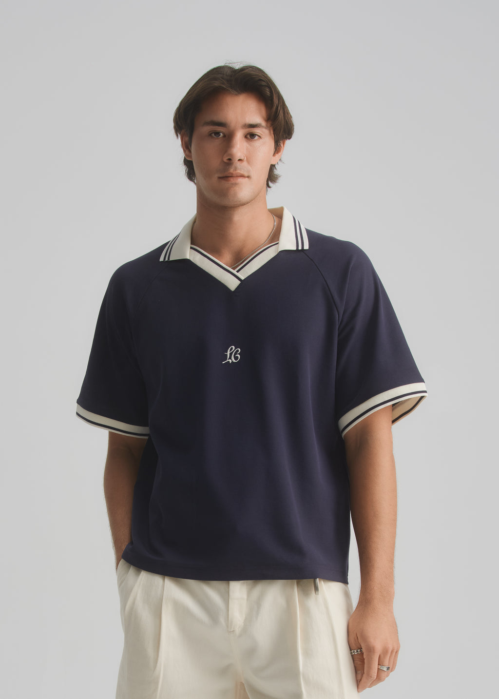 Man wearing a navy blue polo shirt with white trim on a gray background