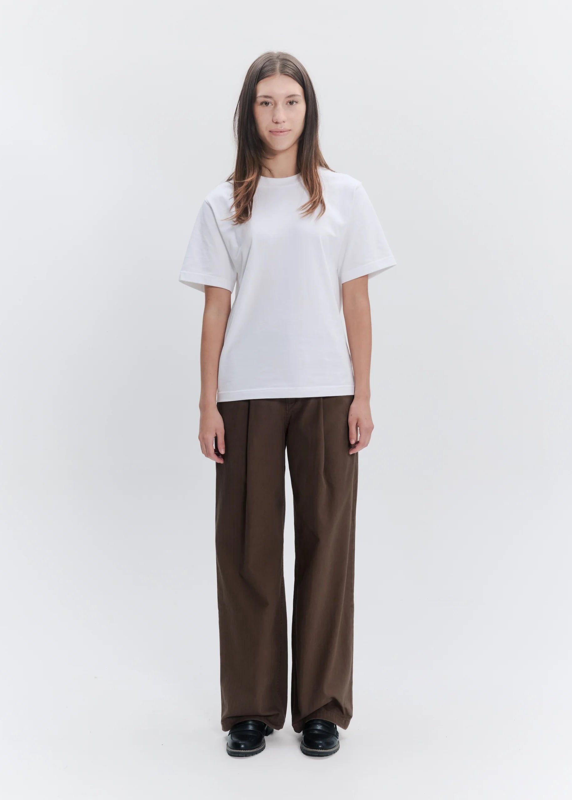 Person wearing a white t-shirt and brown pants on a white background